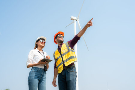 Engineer and architect discussing on wind turbine farm with blue sky background