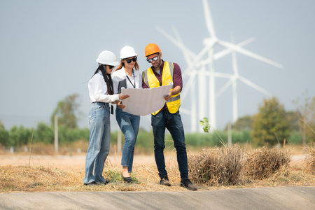 Group of engineers and architects on construction site with wind turbines in backgroundの写真素材