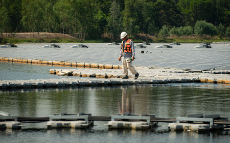 Technician currently evaluating and repairing the transmission terminals for electricity generated by solar energy in a floating solar power system.の写真素材