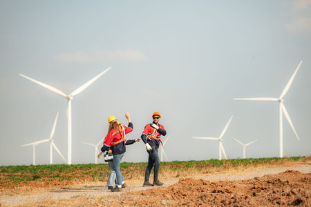 Engineer and technician greet each other in wind turbine farm with blue sky background