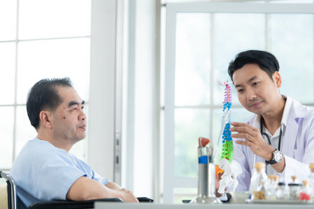 In the hospital office, A medical explains about the spine and its treatment to a patient
