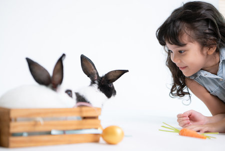 Smiling little girl and with their beloved fluffy rabbit, showcasing the beauty of friendship between humans and animalsの写真素材