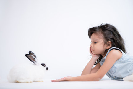 Smiling little girl and with their beloved fluffy rabbit, showcasing the beauty of friendship between humans and animalsの写真素材