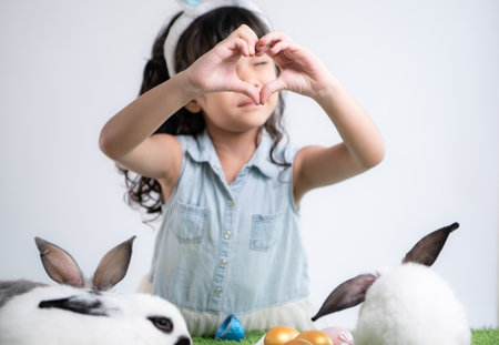 Smiling little girl and with their beloved fluffy rabbit, showcasing the beauty of friendship between humans and animalsの写真素材
