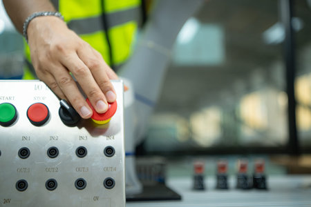 Close-up of hand pressing the stop button on the control panel of an industrial machine.の写真素材