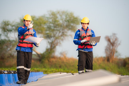 Photovoltaic engineers work on floating photovoltaics. Inspect and repair the solar panel equipment floating on the water.の写真素材