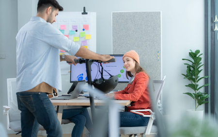 Businessman riding electric scooter in office with colleague in background