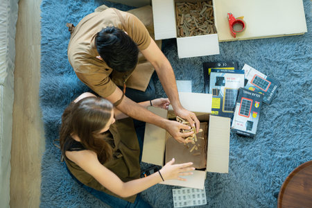 High angle view of young couple packing boxes after selling things online via social media channels.