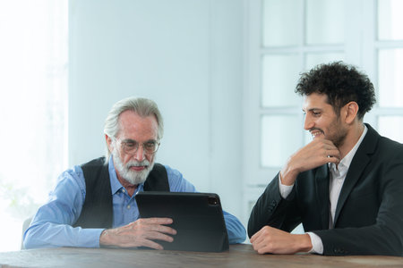 A group of professional businessmen working on tablet in a home office setting, smiling and working...