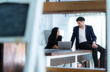 A group of professional businessmen and businesswomen working on tablet in a home office setting,...
