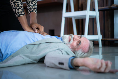 An elderly businessman suffered a sudden heart failure at work, A coworker was administering CPR to offer basic life support.の写真素材