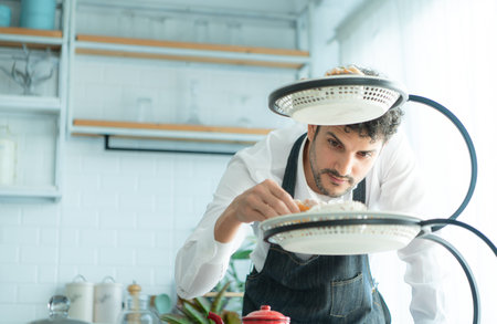 A young man puts on an apron to make dessert to eat with his wife. Checking the completeness of the finished dessert.の写真素材