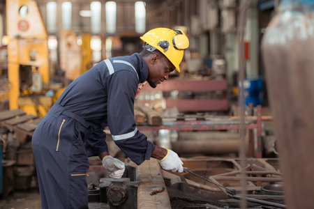 Railway technician in uniform and safety helmet working on train repair station