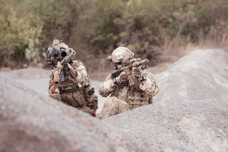Soldiers in camouflage military uniforms carrying weapons, Reconnaissance missions in rugged...