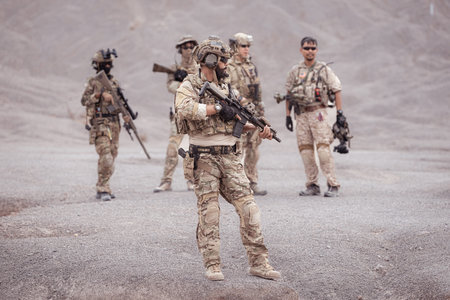 Soldiers in camouflage military uniforms carrying weapons, Reconnaissance missions in rugged...