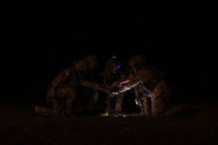 Group of soldiers in camouflage uniforms hold weapons with patrol missions at night