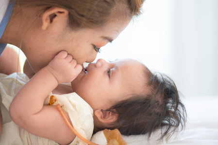 A mother plays with her little daughter in a bedroom full of warmth and family.の写真素材