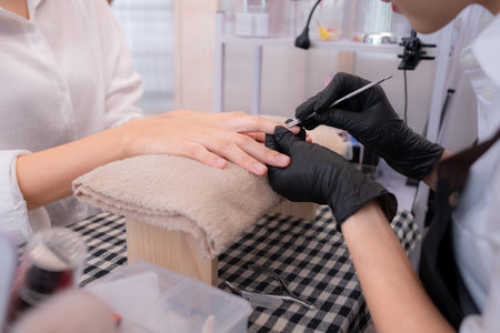 A nail technician is using tools to cut and polish nails of a customer.の写真素材
