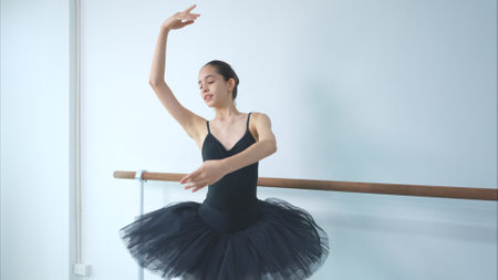 A girl ballet student practices ballet dancing at home with a white backgroundの写真素材