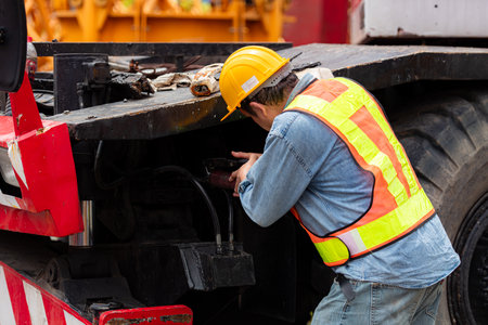 Engineers and technicians grease the wheel axle of a large crane before moving to the construction siteの写真素材