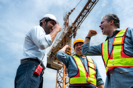 Group of workers at construction site are discussing construction progress with a tower crane in the backgroundの写真素材