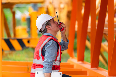 Crane foreman uses walkie-talkie and inspect the construction crane lifting heavy items in the...