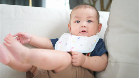 A tiny child sits smiling happily on the couch in the living room