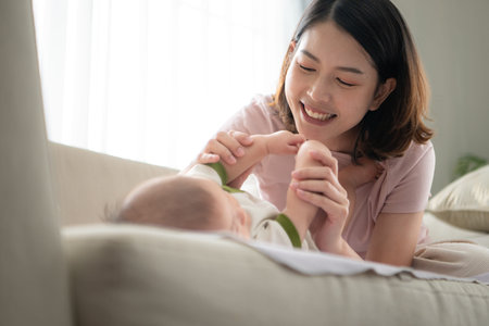 A tiny child smiling happily on the couch in the living room with mom