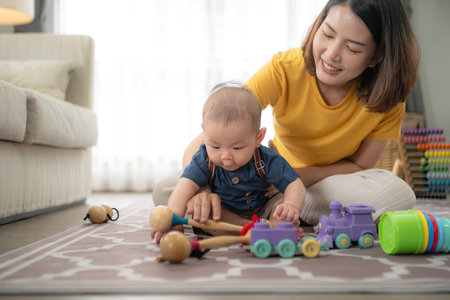 A tiny child cheerfully plays with toys on the floor of the living room with momの写真素材