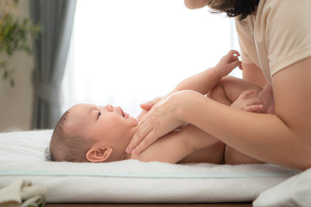 A tiny child smiles happily on the bed waiting for mother apply powder and put on clothes after taking a bathの写真素材