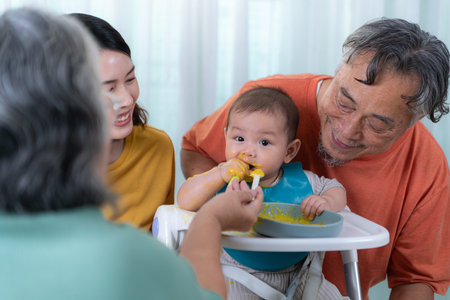 A little child eating his first meal, parents and grandparents cheer excitedly