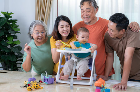 A little child eating his first meal, parents and grandparents cheer excitedly