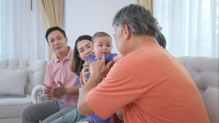 Grandparents and parents with their little child play happily in the living room of the houseの写真素材
