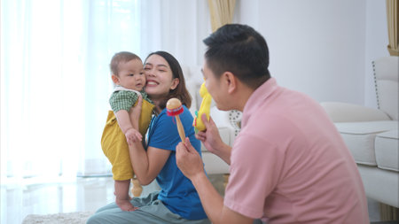 Parents and their little child play happily in the living room of the houseの写真素材
