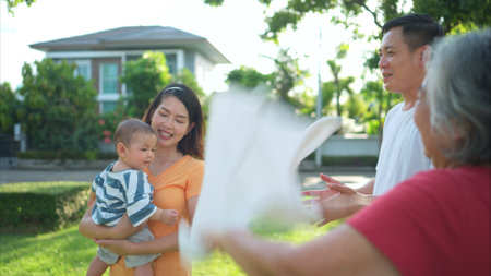 Grandparents and parents with little child are having fun and resting in a parkの写真素材
