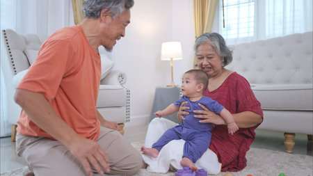 Grandparents and their little grandchild play happily in the living room of the house
