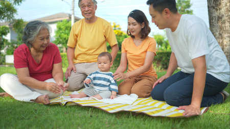 Grandparents and parents with little child are having fun and resting in a parkの写真素材