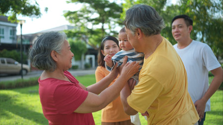 Grandparents and parents with little child are having fun and resting in a parkの写真素材