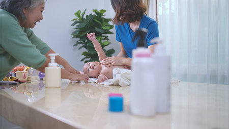 A little child smiles happily waiting for mom and grandma to dry body after taking a bathの写真素材