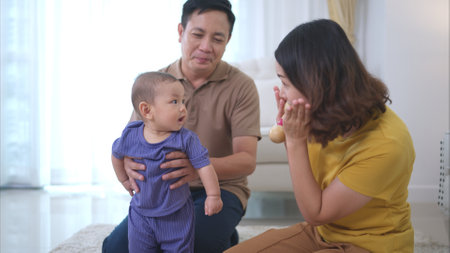 Parents and their little child play happily in the living room of the houseの写真素材