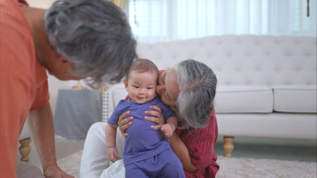 Grandparents and their little grandchild play happily in the living room of the houseの写真素材