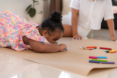 On a holiday, A woman and her little daughters sit on the floor and drawing together in the living roomの写真素材