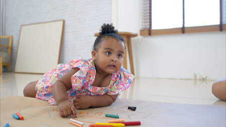 A little girl sit on the floor and drawing in the living roomの写真素材