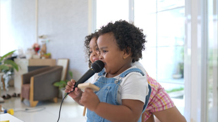 The older sister and younger sister clutching a microphone and sings cheerfully in the living roomの写真素材