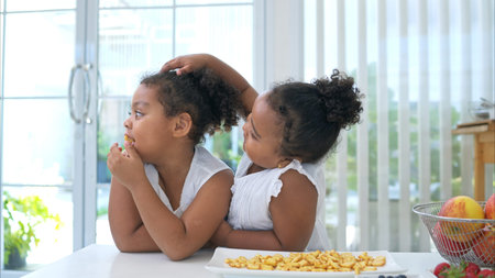 The older sister fed cookies to the younger sister as a snack before the main dinnerの写真素材