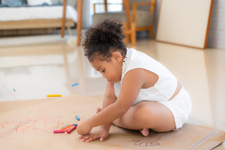 A little girl sit on the floor and drawing together in the living roomの写真素材
