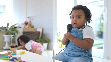 The older sister and younger sister clutching a microphone and sings cheerfully in the living roomの写真素材