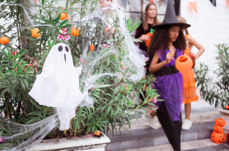 Children in ghost costumes are having fun trick-or-treating on Halloween