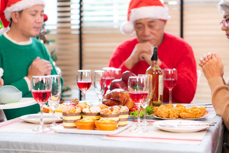 Grandfather leads a prayer and blessing before the family meal during the Christmas celebration at homeの写真素材
