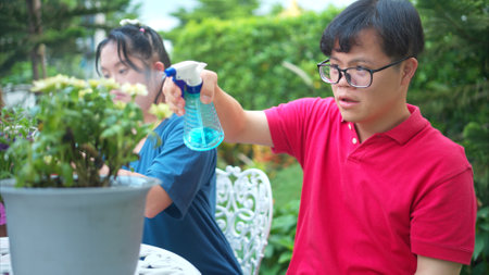 On their day off, Three siblings help water and plant flowers in the front yardの写真素材